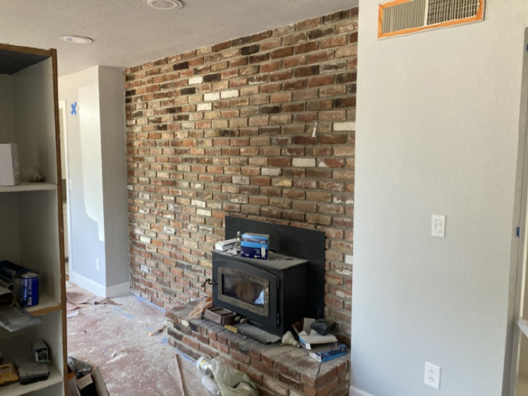 Before living area with brick fireplace wall during renovation